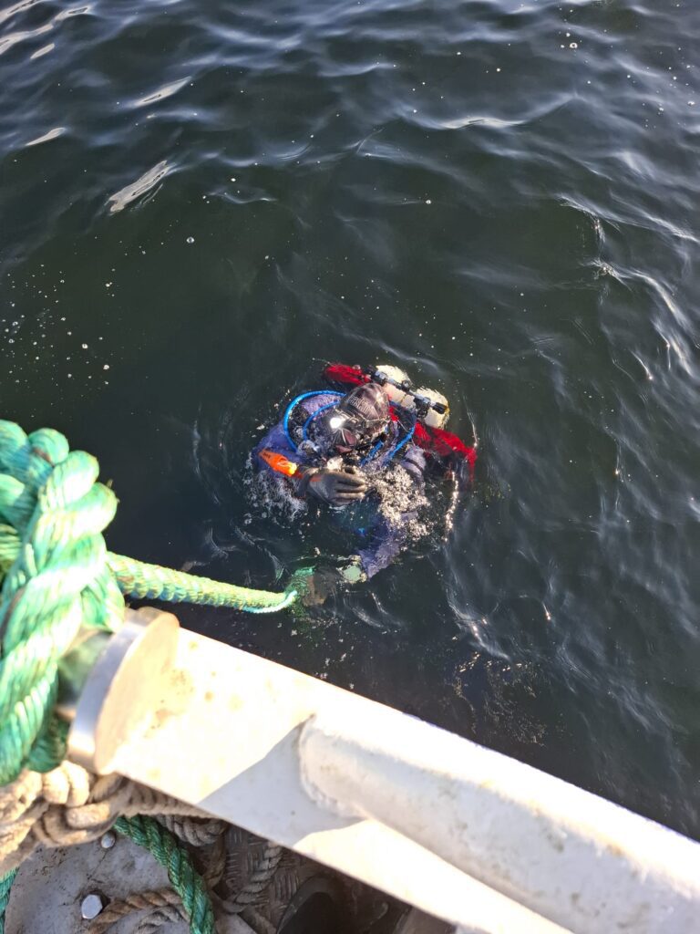 Sukeltaja veneen vieressä, matkalla pinnan alle